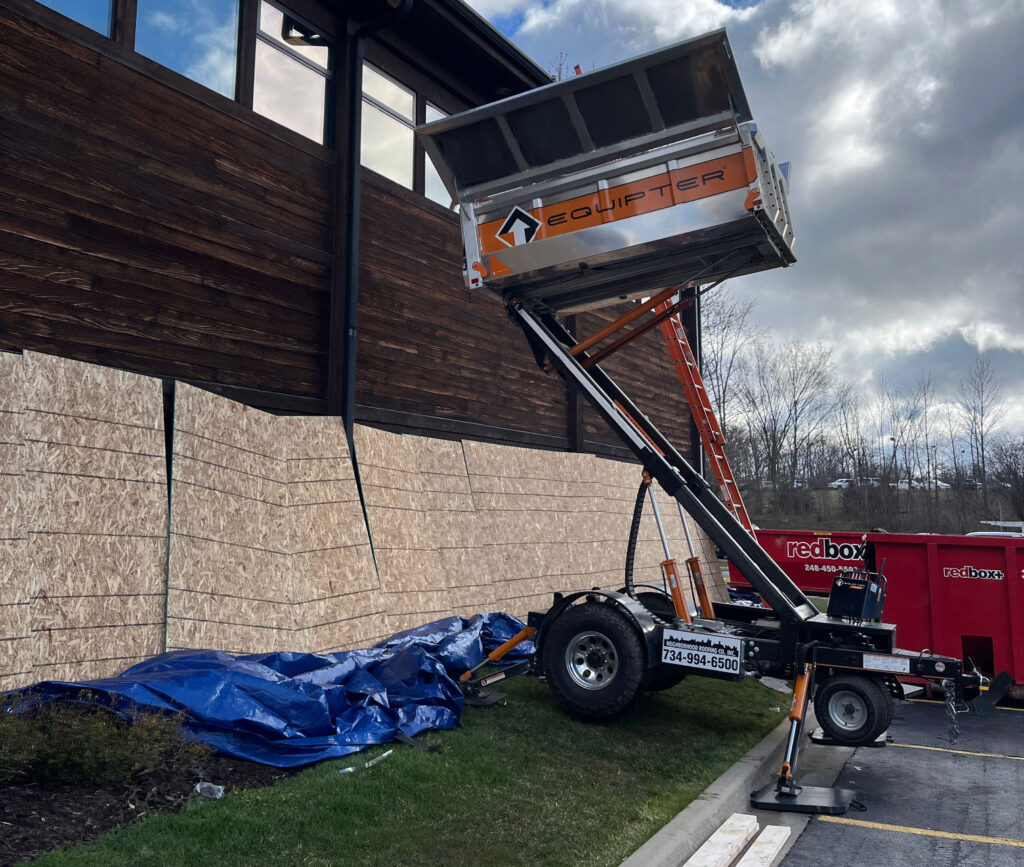 Construction site featuring an Equipter dumpster and renovation efforts on a wooden building.