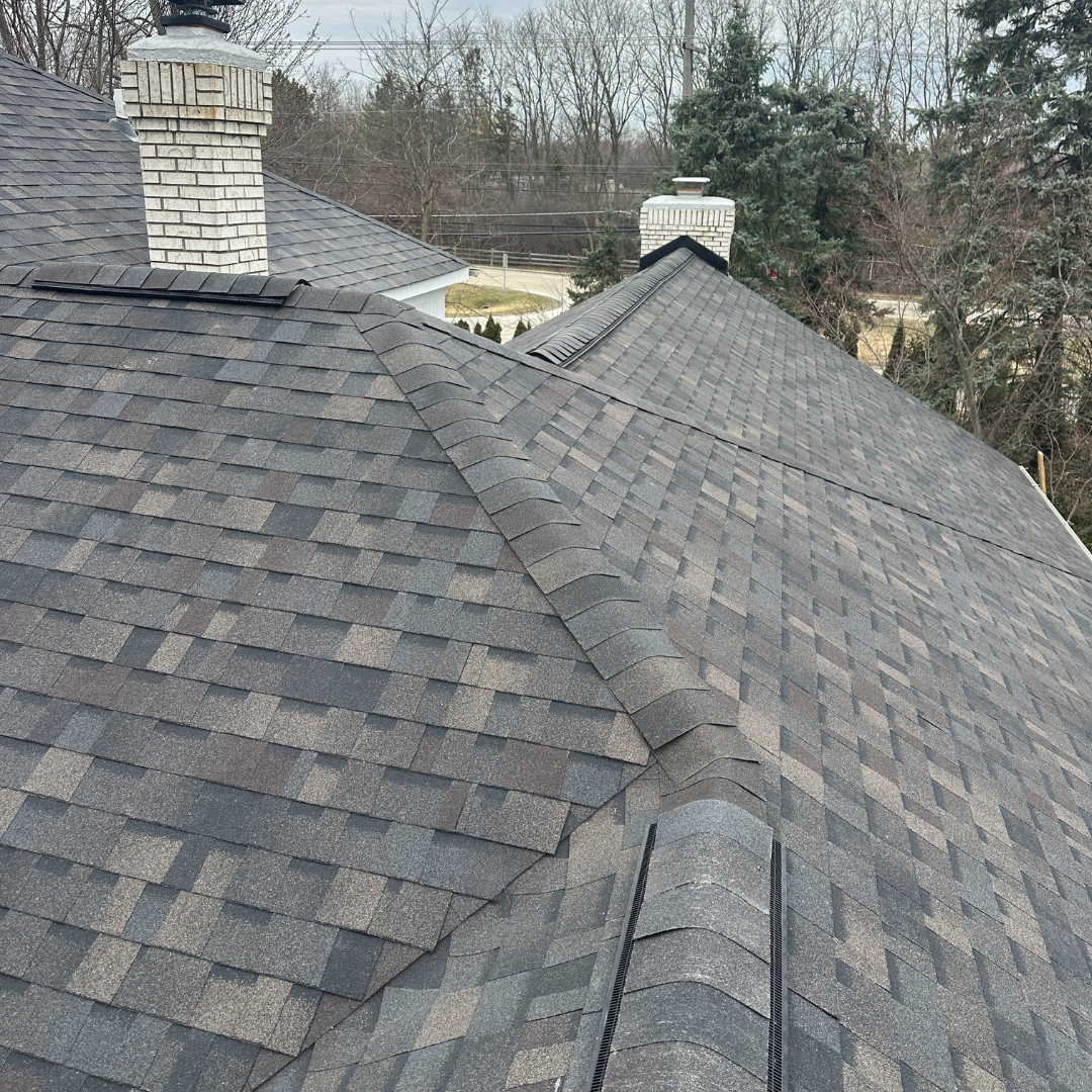 Attractive asphalt shingle roof with chimneys in a serene suburban setting.