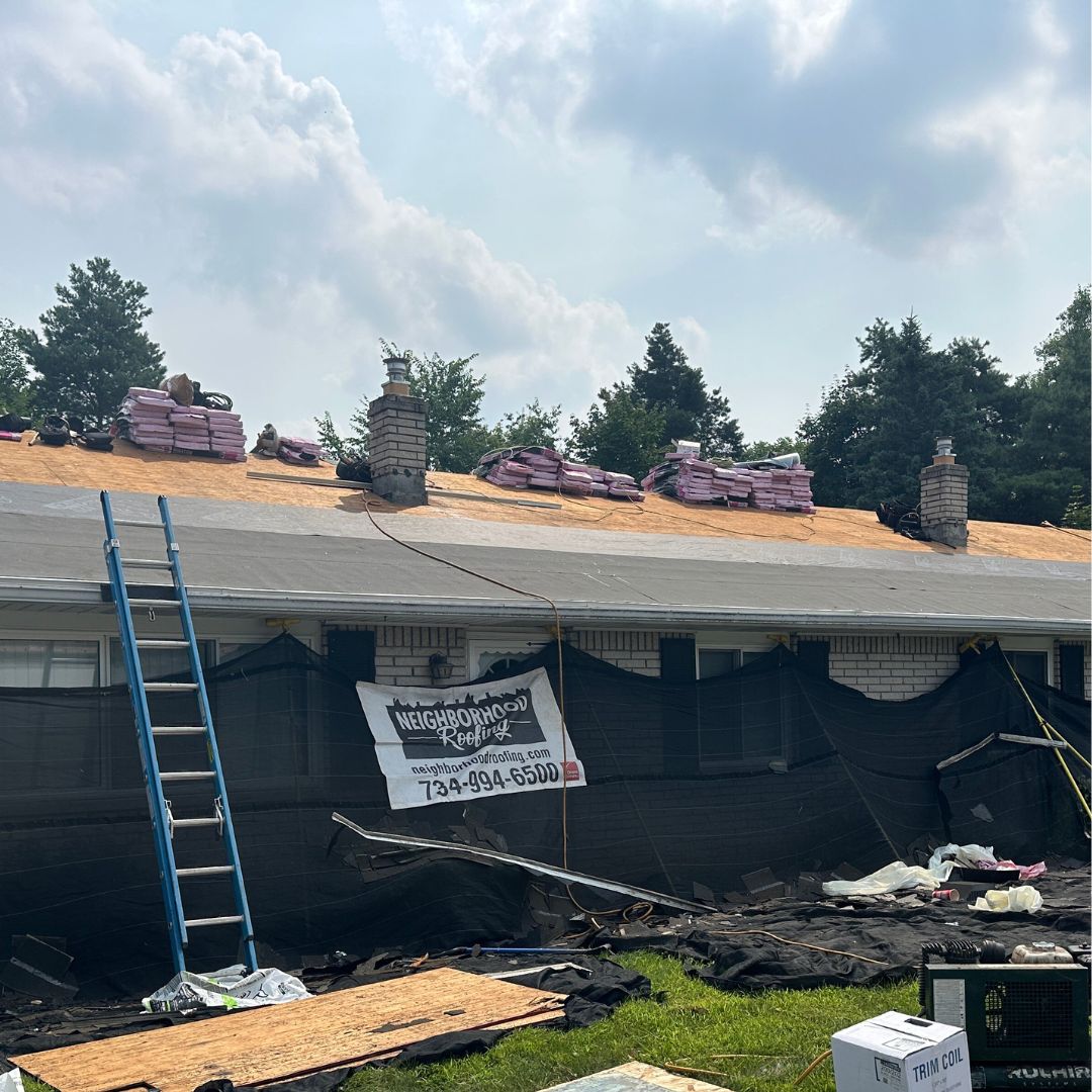 Roof repair in progress by Neighborhood Roofing with materials and safety measures visible.