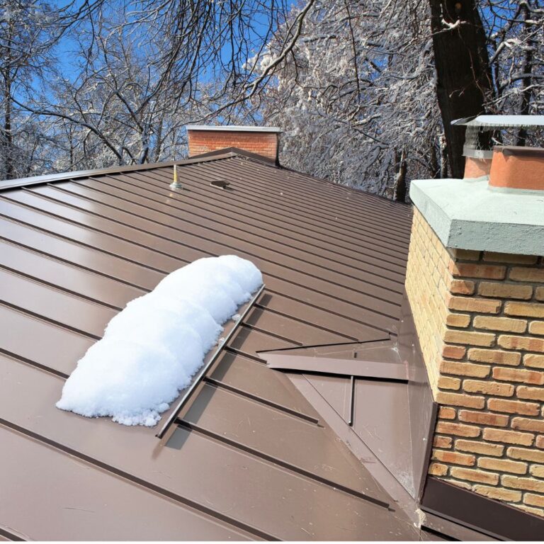 Winter scene of a Neighborhood Roofing design with snow, metal roof, and chimney.