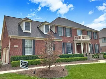 Elegant two-story brick home with manicured landscaping in a charming neighborhood, perfect for families.